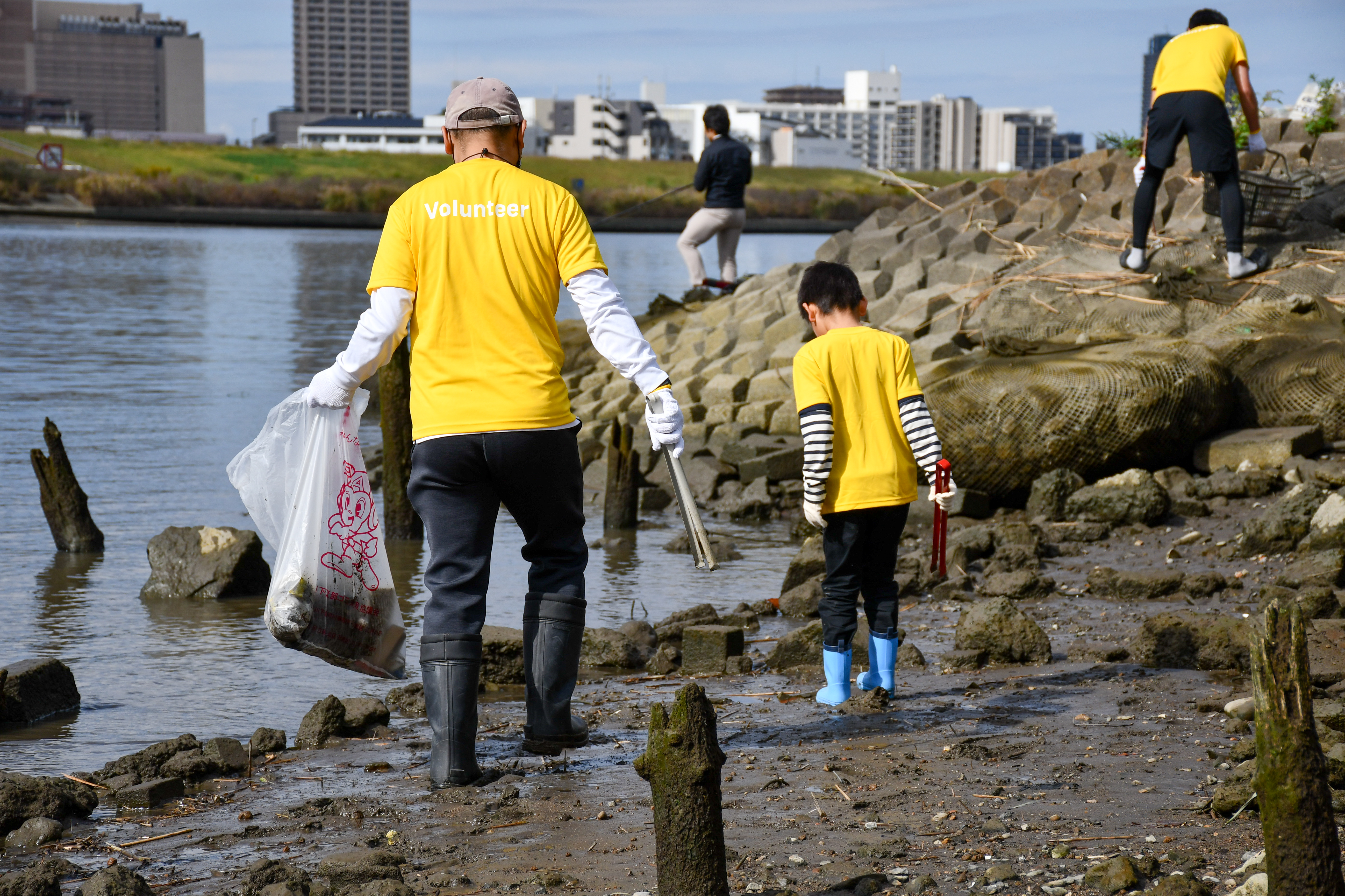 Photo of employees and their families wearing corporate T-shirts cleaning up along the river.