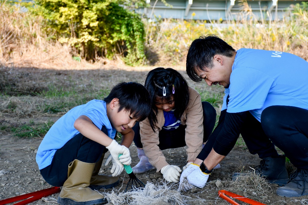 Photo of employees and their families wearing corporate T-shirts cleaning up along the river.